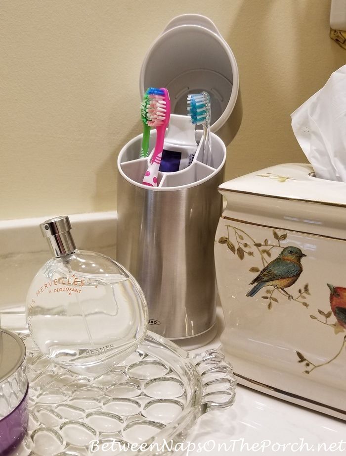 two toothbrushes and a glass container sitting on a counter