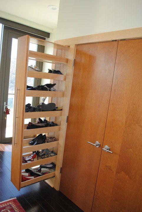 there is a shoe rack in the corner of this room with doors open to reveal shoes