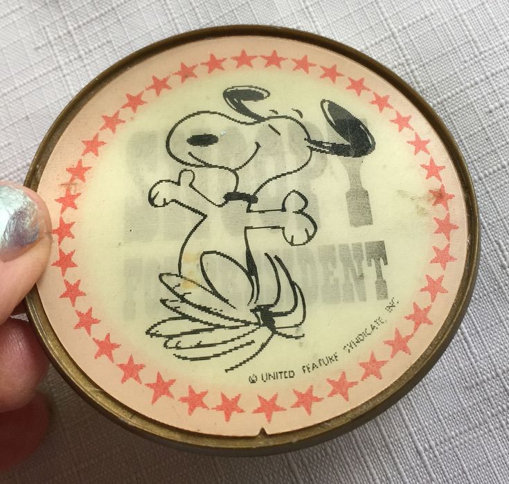 a person holding a small tin with a cartoon character on it's side and red stars around the rim