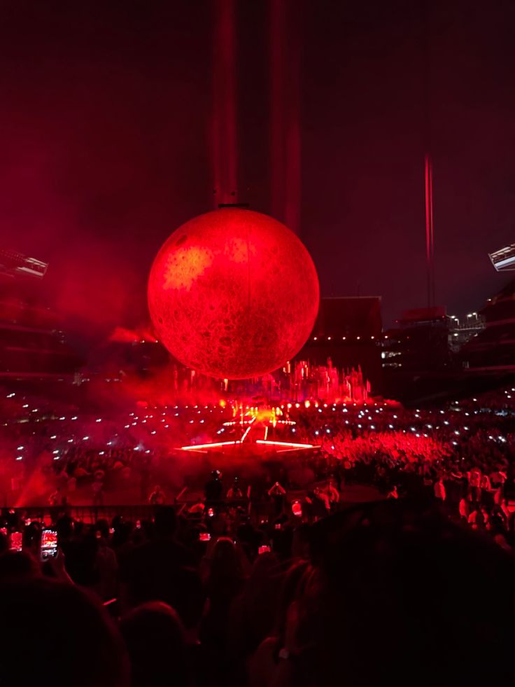 a large red ball sitting on top of a stage in the middle of a crowd