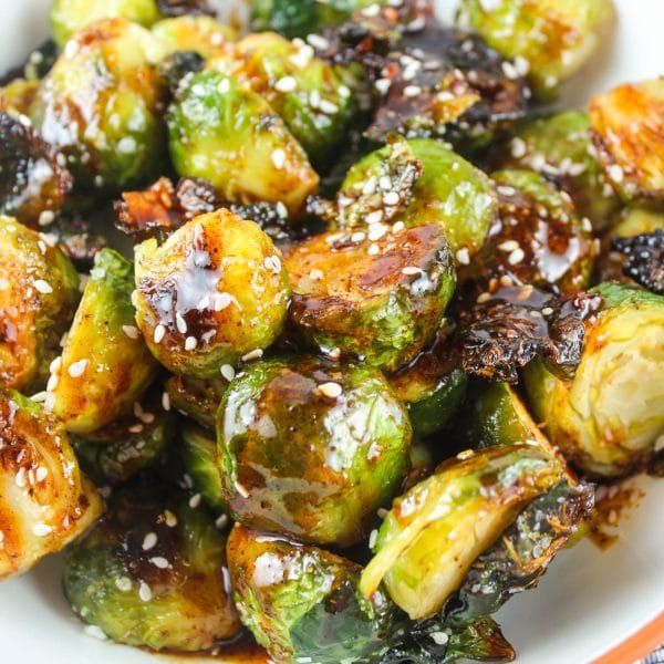 a white plate topped with brussel sprouts covered in sesame seeds and seasoning