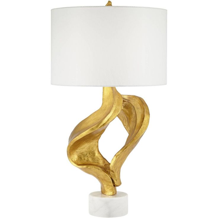 a gold table lamp with a white shade on it's base and an abstract design