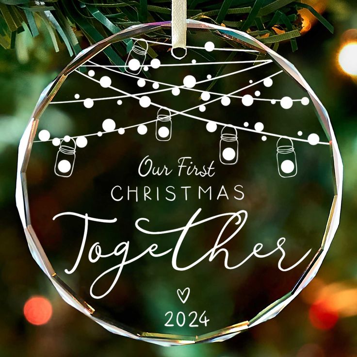 a personalized ornament hanging from a christmas tree with lights in the background