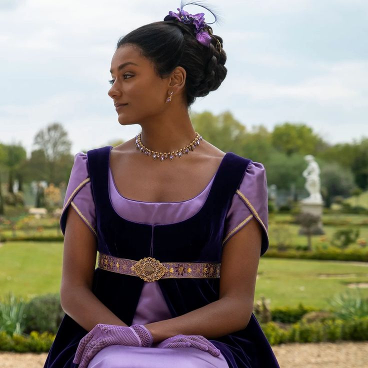 a woman in a purple dress is sitting on a stone bench and looking off into the distance