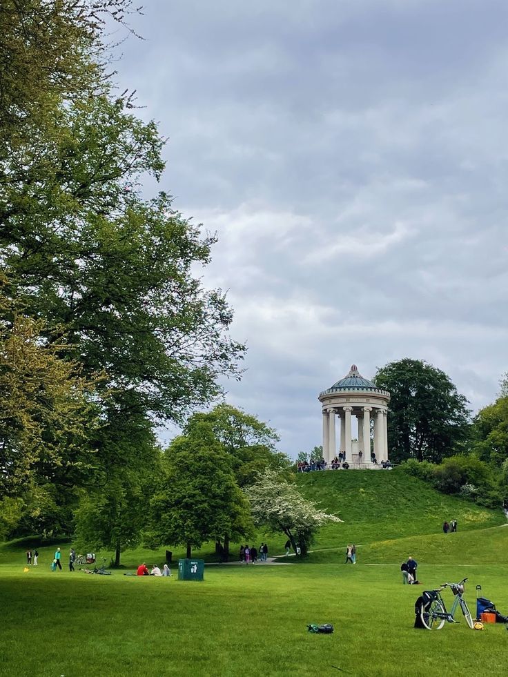 people are sitting on the grass in front of a white building with a green roof