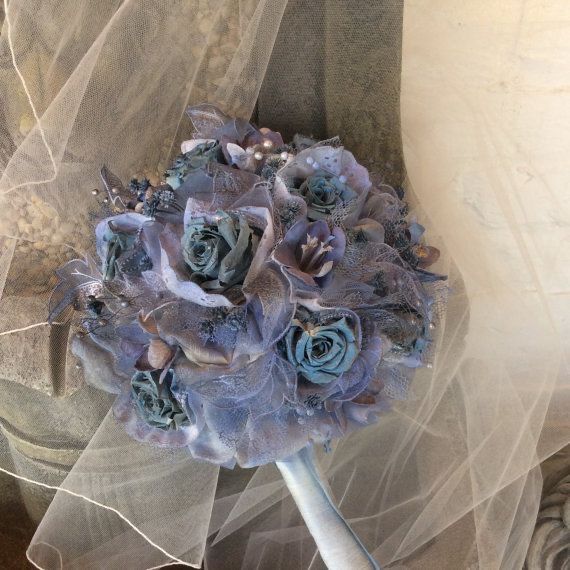 a bridal bouquet with blue flowers and veil on the back of an old chair