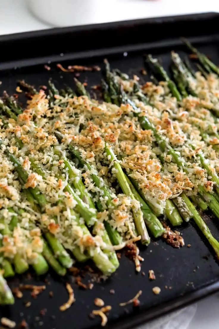 cooked asparagus with parmesan cheese and seasoning on top in a baking pan