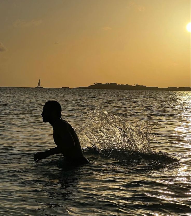 a person is wading in the water at sunset