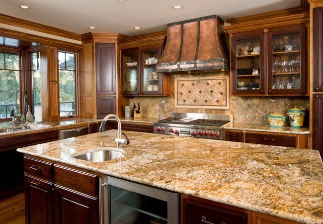 a large kitchen with wooden cabinets and marble counter tops, along with stainless steel appliances