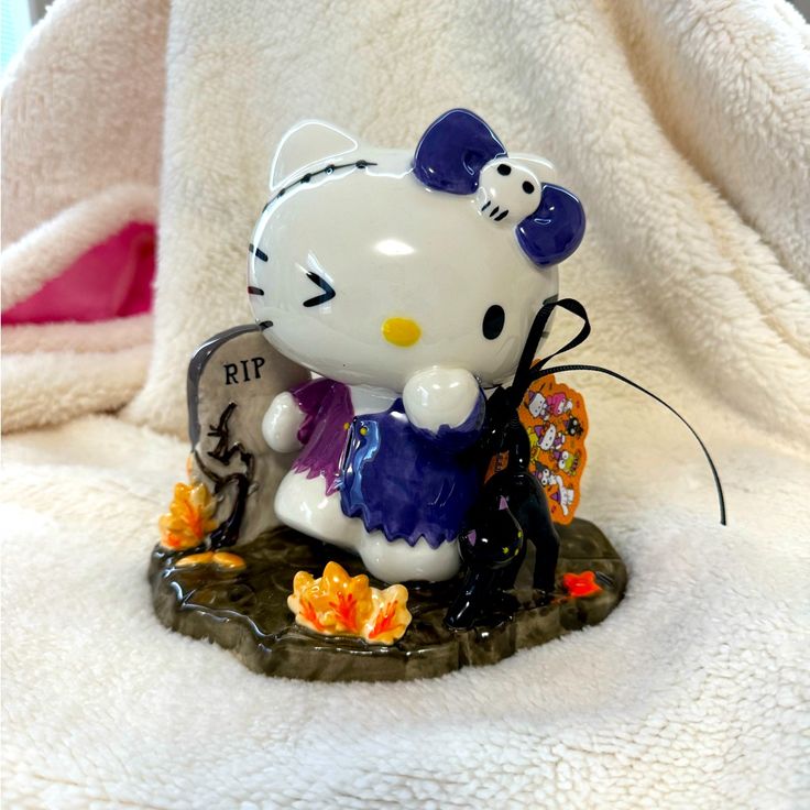 a hello kitty figurine sitting on top of a white towel next to a tree