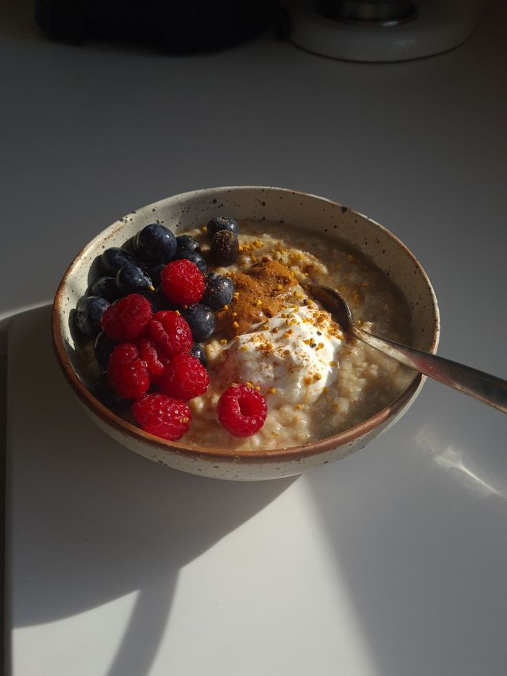 a bowl filled with oatmeal and berries on top of a white table