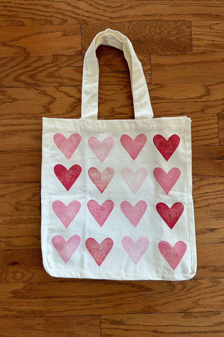 a bag with hearts painted on it sitting on a wooden floor next to a pair of scissors