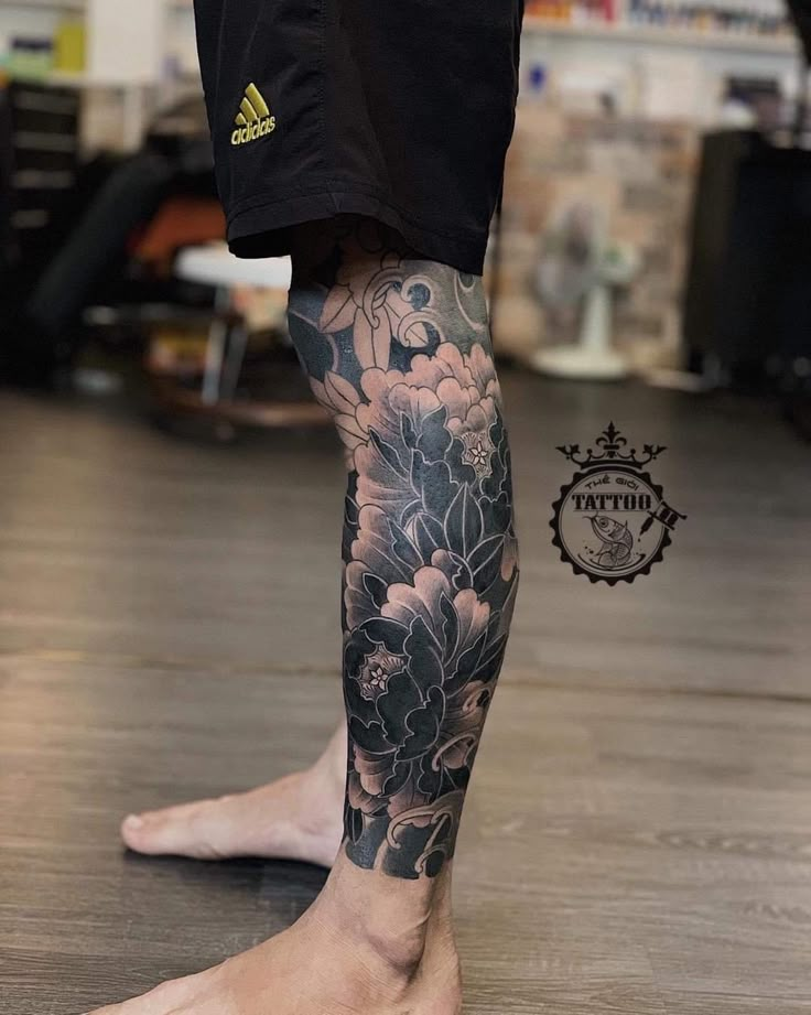 a man's leg with flowers on it and his legs covered in black ink