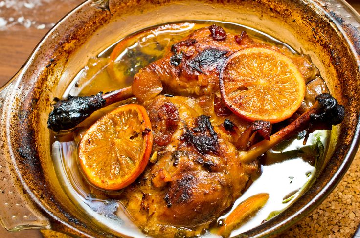 a bowl filled with meat and oranges on top of a table