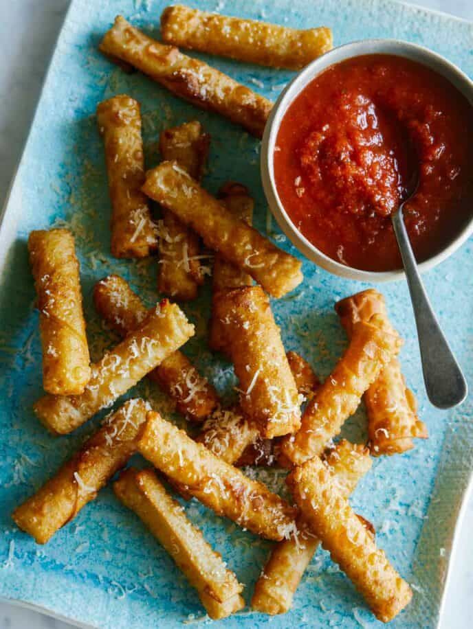 some fried food is on a blue plate with a bowl of ketchup next to it