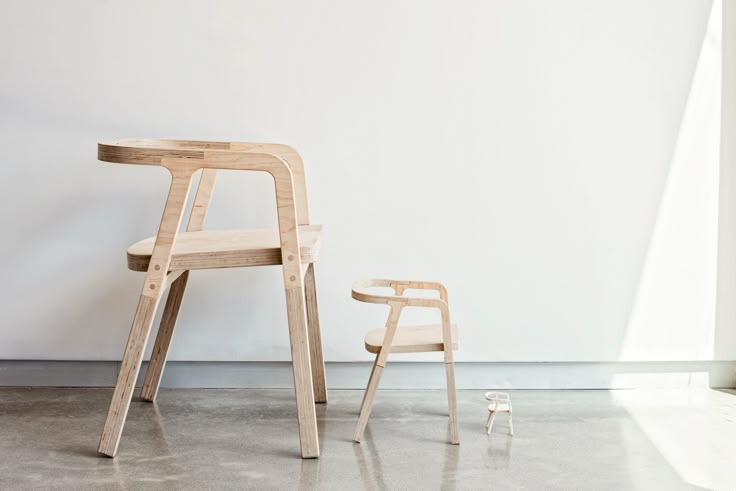 a wooden chair sitting next to a white wall and a small plastic toy on the floor