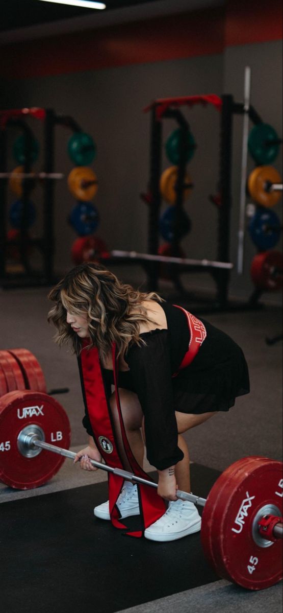 a woman squats down while holding a barbell