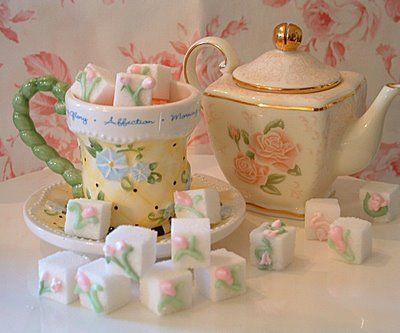 a tea pot and some sugar cubes sitting on a table next to a cup