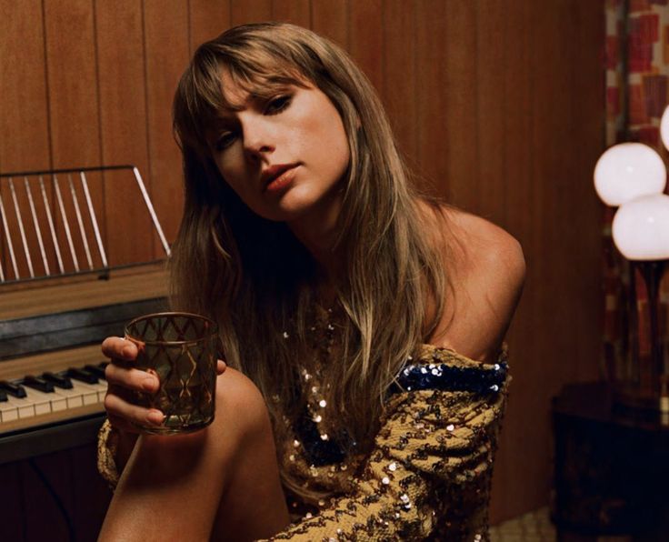 a woman sitting in front of a piano holding a cup