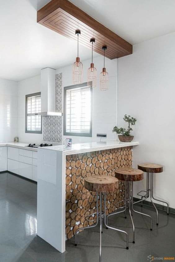 a kitchen with three stools next to a bar made out of tree trunks and logs