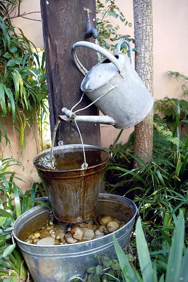 two buckets filled with water sitting on top of each other in front of plants