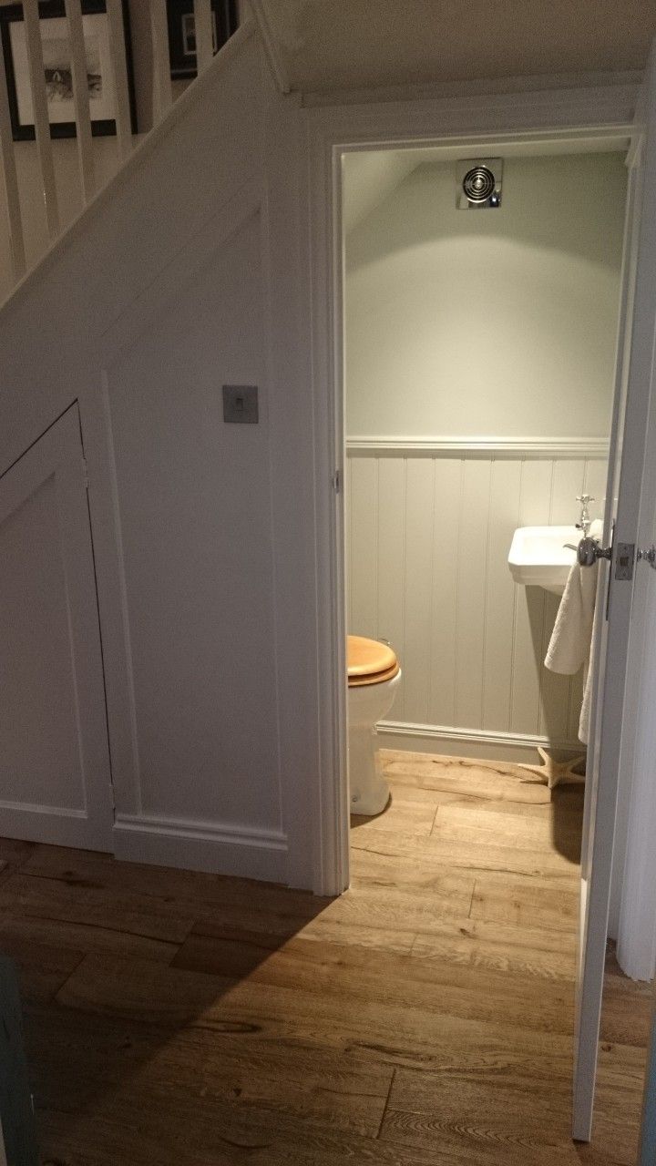 an open door leading to a bathroom with a sink and toilet in the corner next to stairs