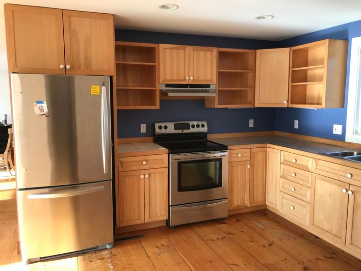 an empty kitchen with wooden cabinets and stainless steel appliances in the middle of the room