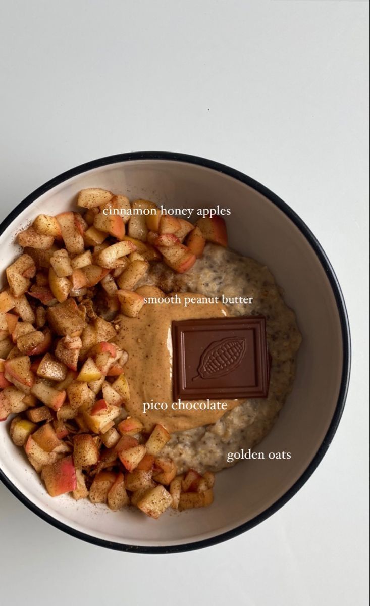 a bowl filled with oatmeal and apples next to a bar of chocolate