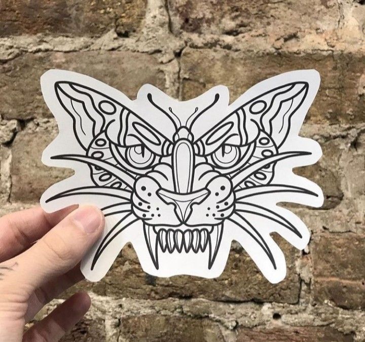 a hand holding up a sticker with an image of a cat's face