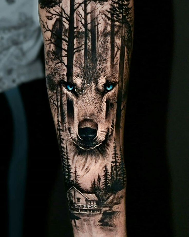 a man's arm with a wolf tattoo on it and trees in the background