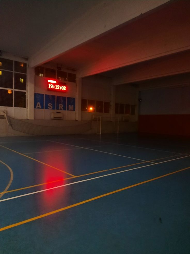 an empty basketball court with the lights on at night, and no one is in it