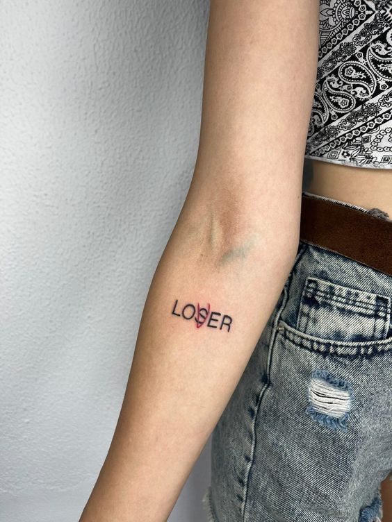 a woman with a tattoo on her arm that reads,'loser'in red ink