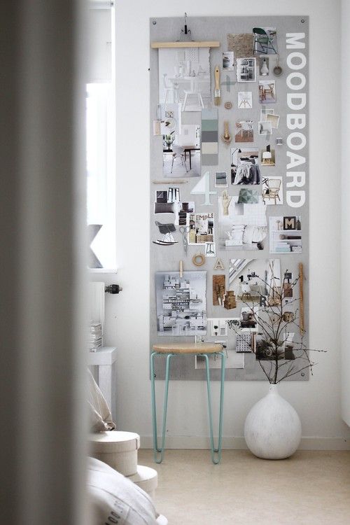 there is a white vase sitting in front of a wall covered with pictures and letters