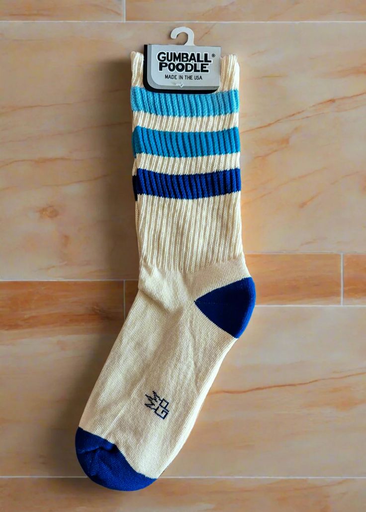 Takin' it back to the '70s and '80s with these retro socks! Features a more relaxed fit for ultimate comfort and a gentle feel around the calf. Wear them pulled up or scrunched down. Made of natural cotton with accents of royal blue cotton, Columbia blue nylon, and factory blue nylon. Super comfy, unisex, one-size-fits-most, and made in the USA. Features: Unisex Gym Crew Socks Wide Rib knit Cushioned foot = extra comfort! Seamless toe Cream colorway with variated blue stripes Leg height: 8" unstretched (measured from heel seam to cuff) USA made Brand & Fabric Content: Brand: Gumball PoodleMaterials: 61% cotton 36% nylon 3% spandex | Machine wash cold, line dryMade in: USA Fit: Wide ribbed socks reach to mid-calf on most folks & fit a women’s US size 6 to men’s size 15. As a thicker weave, Retro Socks, Retro Gym, Ribbed Socks, Alice Blue, Ankle Length Skirt, Columbia Blue, Calf Socks, Sock Gifts, Crew Socks