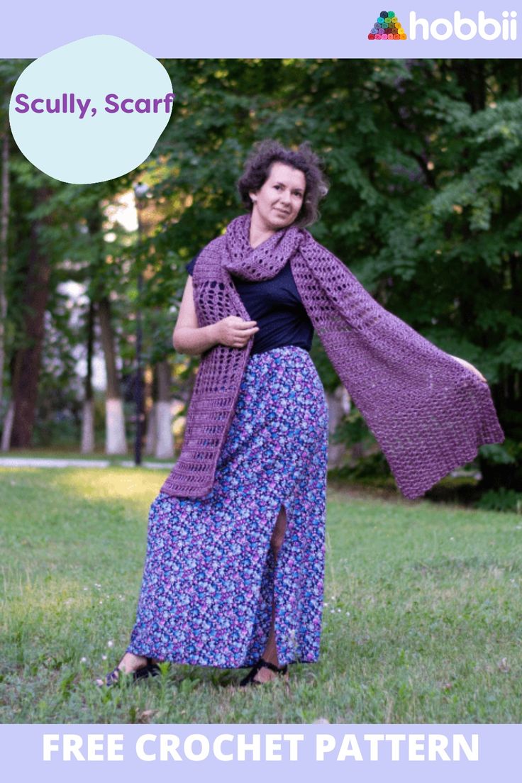 a woman is standing in the grass wearing a purple knitted shawl and black top