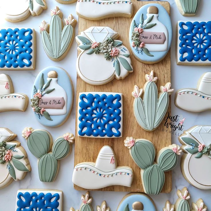 many decorated cookies are on a table with blue and white decorations, including cactuses