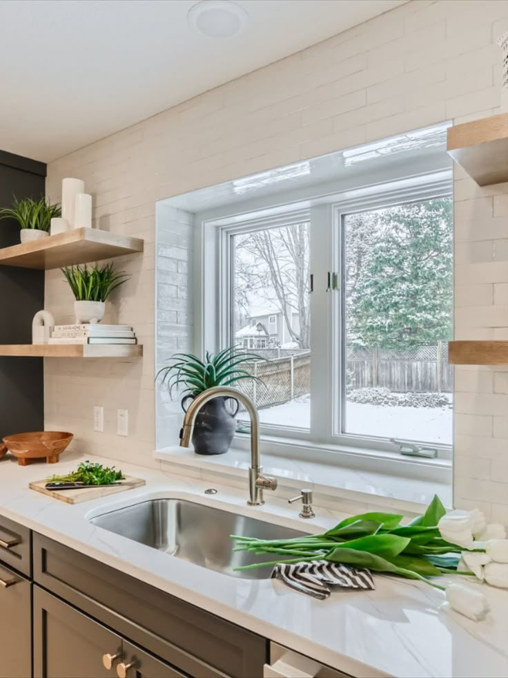 Go to the link to see more see this kitchen reno. This kitchen window above the sink has a ledge with a slab of quarts and surrounded by tile. Floating shelves on both sides of the window. Cabinets On Either Side Of Window, Kitchen Sink Near Window, Kitchen Sink By The Window, Kitchen With Sink By Window, Double Window Kitchen Sink, Tile Around Windows In Kitchen, Kitchen Shelves Beside Window, Open Shelves Beside Kitchen Window, Floating Shelves Next To Kitchen Window