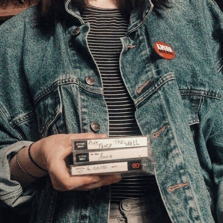 a woman wearing a jean jacket holding three cassettes