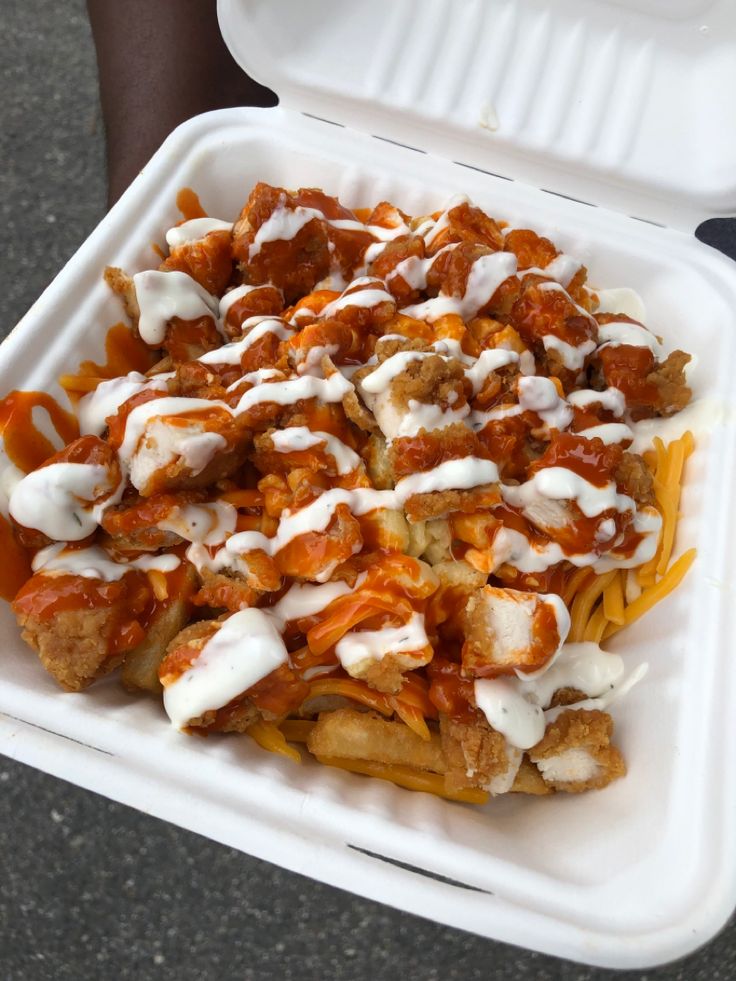 a takeout container filled with pasta and meat covered in sauce, cheese and ketchup