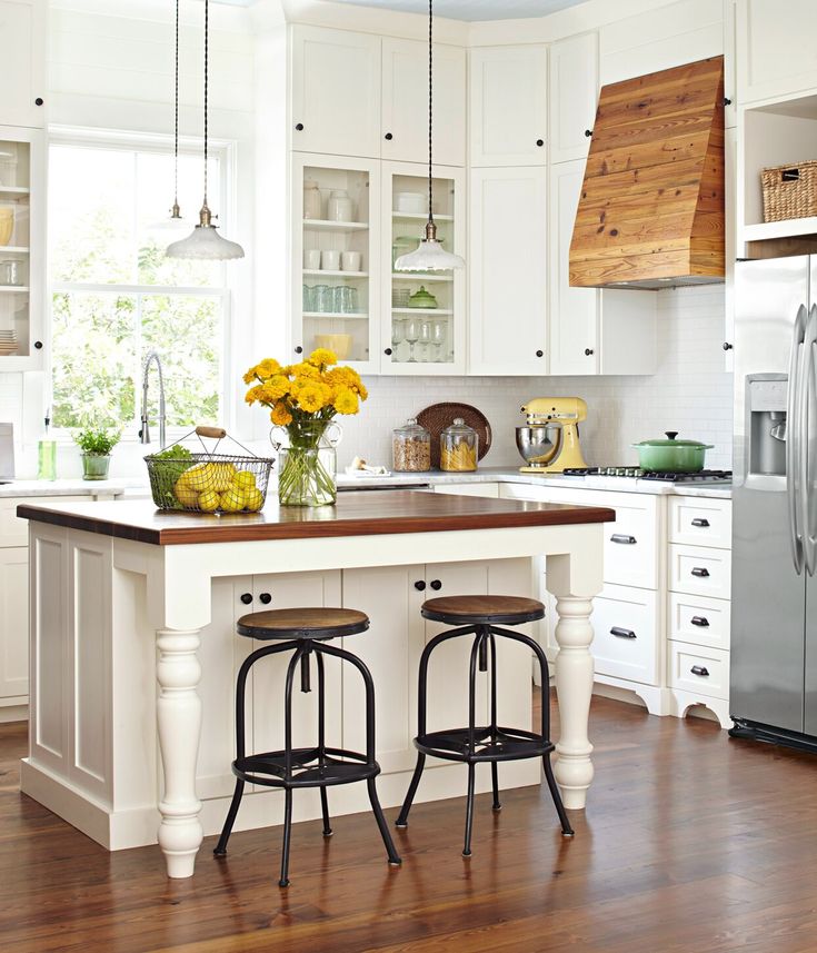 a kitchen with two stools at the island and yellow flowers on the counter top