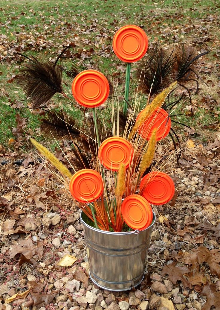 there are many orange flowers in a bucket on the ground with leaves and grass around it