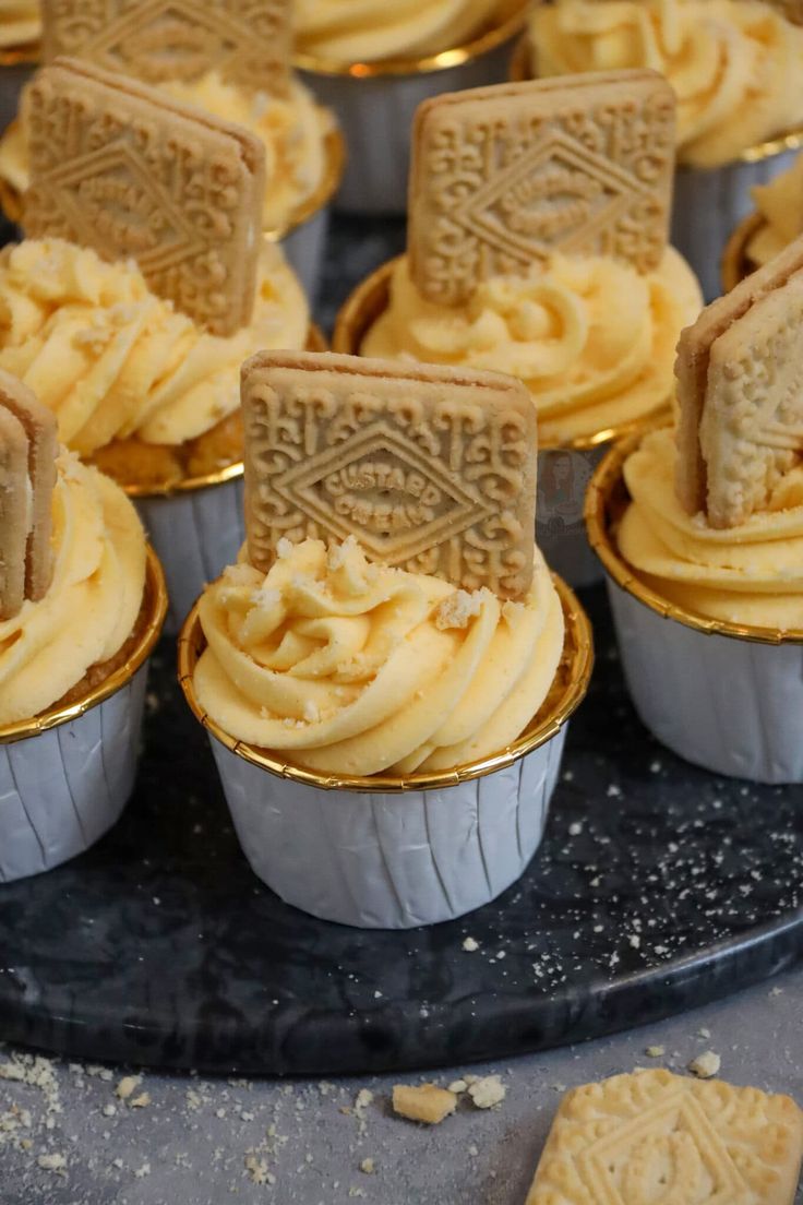 some cupcakes are sitting on a black plate with gold trimming and frosting