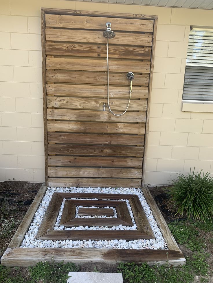 an outdoor shower made out of wood and pebbles