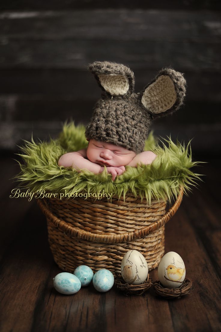 a newborn baby is sleeping in a basket with three eggs and an easter bunny hat