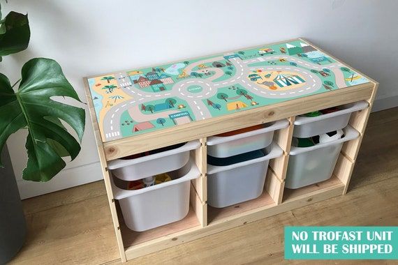 a toy table with bins and toys on it next to a potted plant