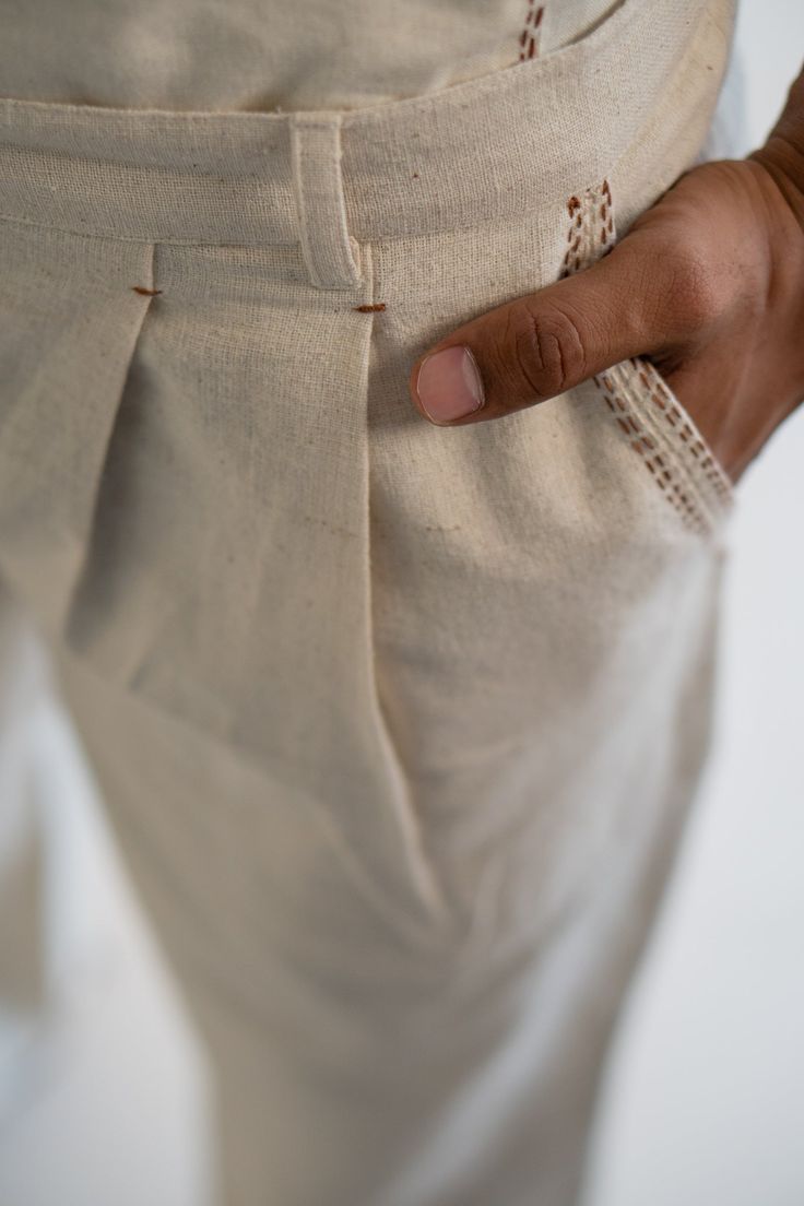 This Dawning Pleated Pants comes in a calm and soothing color. This 30s cotton pant is undyed and unbleached. Flattering mid-waist design with a straight-fit silhouette. Practical touches include side pockets, button-down fly, and belt loops. The pockets and hem are highlighted with the stitches of Kantha, a form of Indian hand embroidery to bring character to the garment. *This item is a final sale and not eligible for returns or exchanges. *This item can take up to 14 business days to ship as Beige Tapered Leg Chinos With Belt Loops, Cream Straight Leg Pants With Welt Pockets, Tapered Cotton Bottoms With Belt Loops, Cream Straight Pants With Belt Loops, Cream Wide Leg Pants With Patch Pockets, Loosely Fitted Cotton Pants With Belt Loops, Cotton Straight Leg Pants With Button Closure, Cream Linen Pants With Pockets, Cream Linen Tapered Leg Bottoms