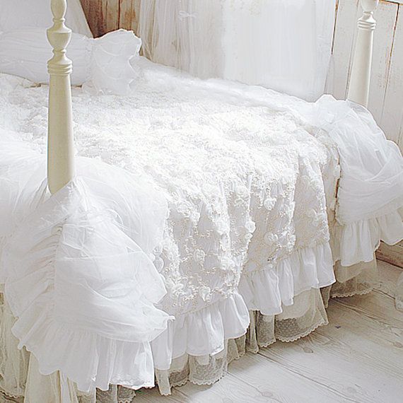 a white bed with ruffled bedspread and pillows