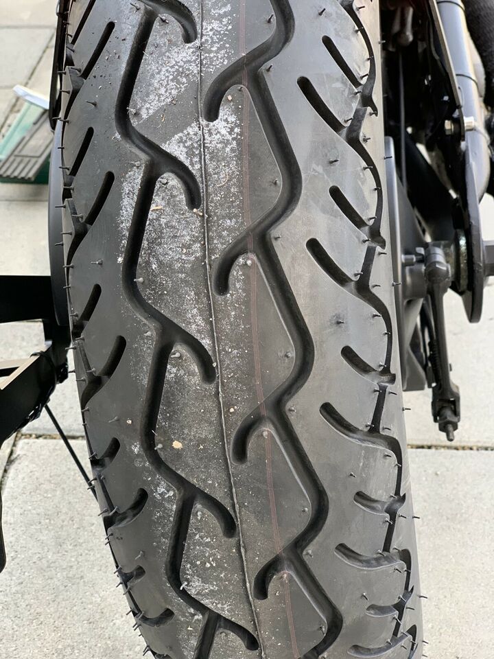 the front tire of a motorcycle parked on the sidewalk