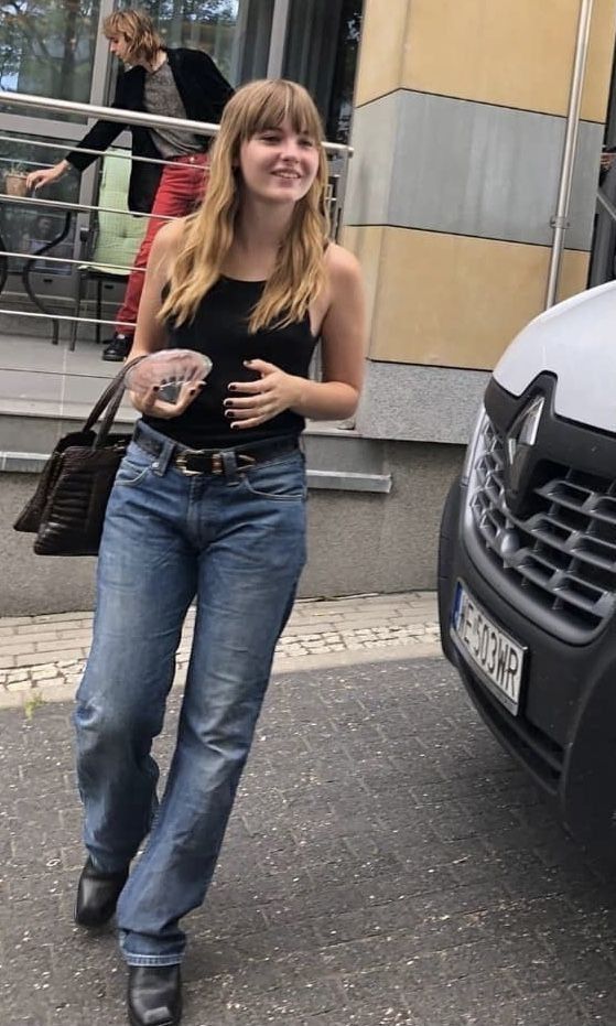 a woman walking down the street in front of a car