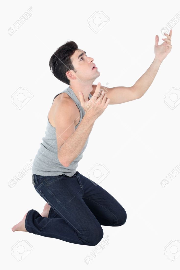 a man kneeling on the ground with his hand up to catch a frisbee